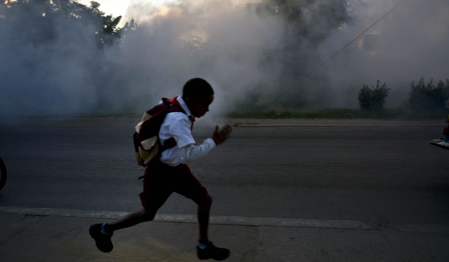A student runs past fumigation fog, sprayed to kill Aedes Aegypti mosquitos, in Pinar del Rio, Cuba, Tuesday, March 1, 2016. Authorities are fumigating in an attempt to prevent the spread of Zika, Chikungunya and Dengue. (AP Photo/Ramon Espinosa)