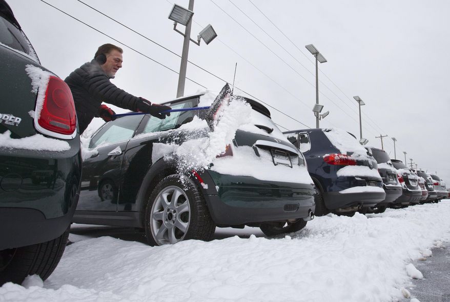 Mike Kelly cleans snow off cars at The Sharpe Collection, in Grand Rapids, Mich., Tuesday, March 1, 2016. (Cory Morse/The Grand Rapids Press via AP)