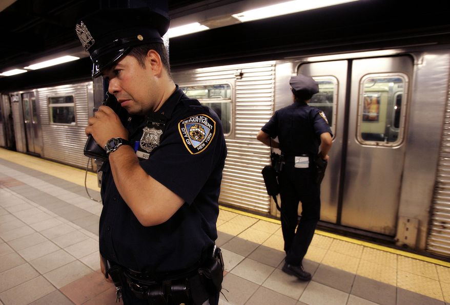 FILE - In this July 8, 2005 file photo, New York City police officer Frank Gotay listens to a message on his radio as his partner Yolanda Cortes waits for a subway car's doors to open while performing random checks along the platform at the 42nd Street station in New York. New York City transit officers can finally communicate on their radios with police above ground. (AP Photo/Julie Jacobson, File)