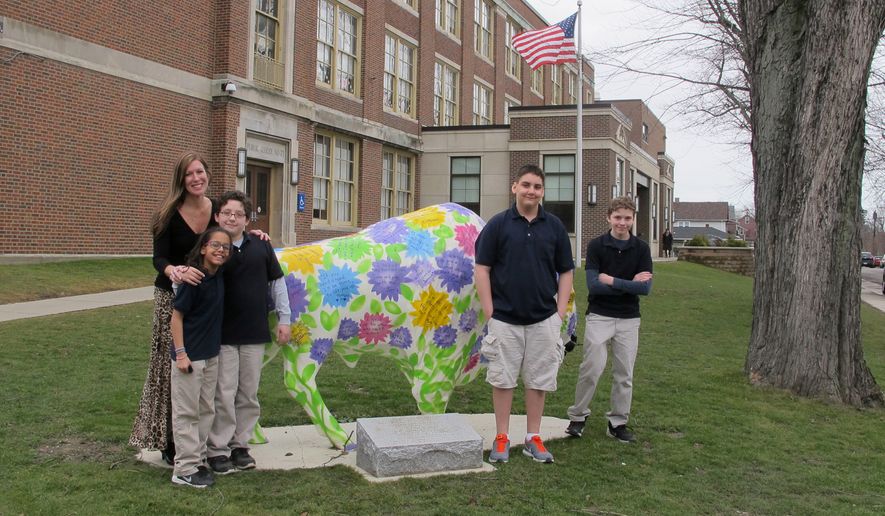 In this Feb. 29, 2016, file photo, teacher Kelly Gasior, left, and students, from left, Olivia Mashtaire, Ryan Lysek, Christian Vazquez and Tyler Lysek stand with a statue of a Buffalo that's been emblazoned with anti-bullying messages outside Lorraine Academy, Public School No. 72, in Buffalo, N.Y. (AP Photo/Carolyn Thompson)