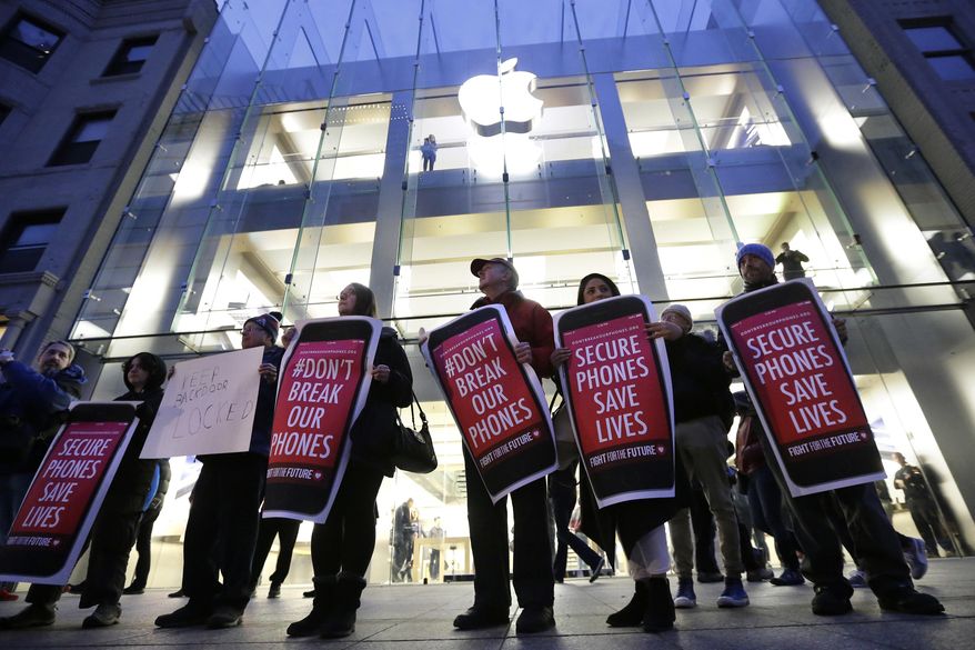 FILE - In this Tuesday, Feb. 23, 2016, file photo, protesters carry placards outside an Apple store in Boston. Tech companies, security experts and civil liberties groups are filing court briefs supporting Apple in its battle with the FBI. The groups oppose a judge’s order that would require Apple to help federal agents hack an encrypted iPhone used by a San Bernardino mass shooter. (AP Photo/Steven Senne, File)