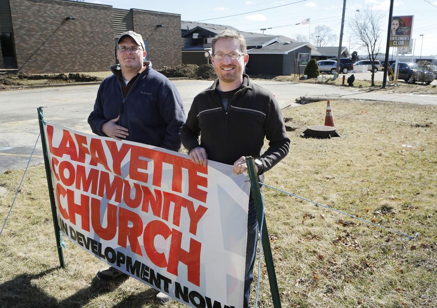 Associate pastor Billy Hardy, left, and pastor Jeff Mikels stand outside the new Lafayette Community Church in Lafayette, Ind., Wednesday, March 2, 2016, The church will be next door neighbors with Filly's Gentlemens Club, background. (John Terhune/Journal & Courier via AP)