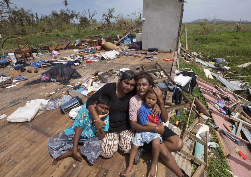 FILE - In this Feb. 24, 2016, file photo, Sanjogeeta Kiran, right, with her sister Sulva Kiran, second left, and her children Shivendera, left, and Raajeen, sit amid the debris of their home in RakiRaki, Fiji, after cyclone Winston ripped through the island nation. The cyclone which tore through Fiji two weeks ago was so powerful that at the Namena Island Resort, it ripped out a commercial oven and tossed it half the length of a football field. The cyclone not only ripped apart thousands of homes, it also tore at the fabric of the South Pacific nation’s economy. Apart from tourism, which accounts for one-third of GDP, it also wiped out a significant chunk of the sugar crop, another big source of foreign income. (Brett Phibbs/New Zealand Herald via AP, File) NEW ZEALAND OUT, AUSTRALIA OUT
