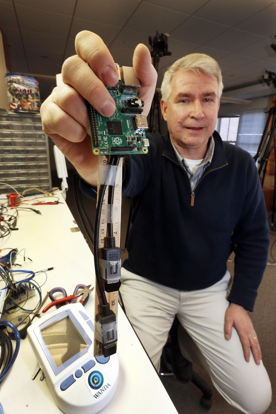 In this photo taken Wednesday March 2, 2016 in Hanover, N.H., Dartmouth College grad student Tim Pierson holds a prototype called "wanda" that can connect a medical devise to a WiFi network. Researchers envision it being used in homes so doctors could remotely monitor a patient's blood pressure.(AP Photo/Jim Cole)