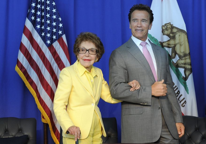 Nancy Reagan, left, is escorted by California Governor Arnold Schwarzenegger after the ceremonial signing of California Senate Bill 944 and Assembly Bill 1911 honoring President Ronald Reagan for his life&#39;s accomplishments and contributions to California on Wednesday, July 28, 2010, at the Ronald Reagan Presidential Library in Simi Valley, Calif. (AP Photo/Adam Lau)