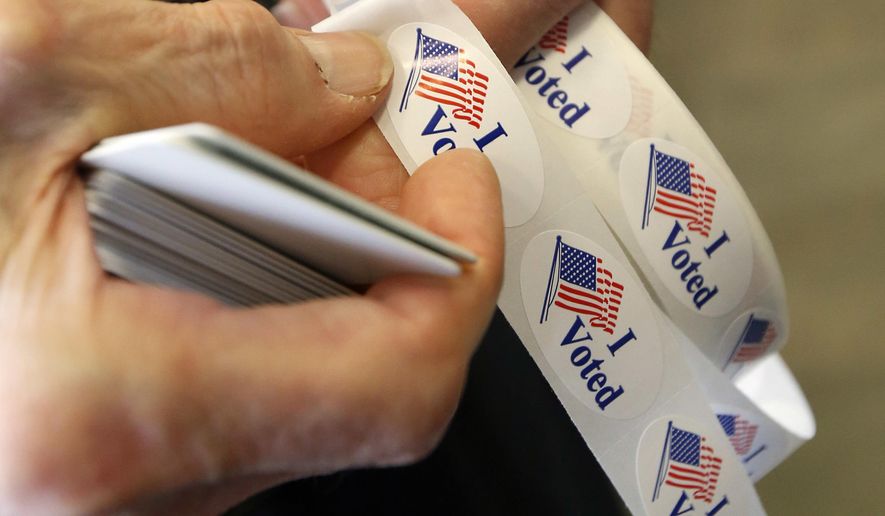 Robert Hughes, a Madison County poll worker removes an "I Voted" sticker to put on the lapel of a voter during the primary election at the precinct in the Highland Colony Baptist Church in Madison, Miss., on Tuesday, March 8, 2016. Mississippi holds its presidential and congressional primaries today. (AP Photo/Rogelio V. Solis)