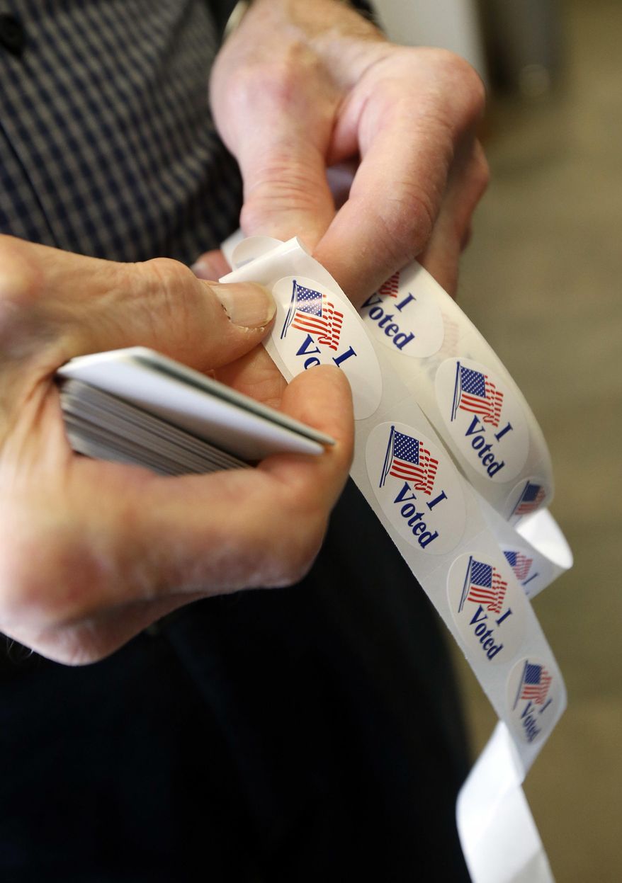 Robert Hughes, a Madison County poll worker removes an "I Voted" sticker to put on the lapel of a voter during the primary election at the precinct in the Highland Colony Baptist Church in Madison, Miss., on Tuesday, March 8, 2016. Mississippi holds its presidential and congressional primaries today. (AP Photo/Rogelio V. Solis)