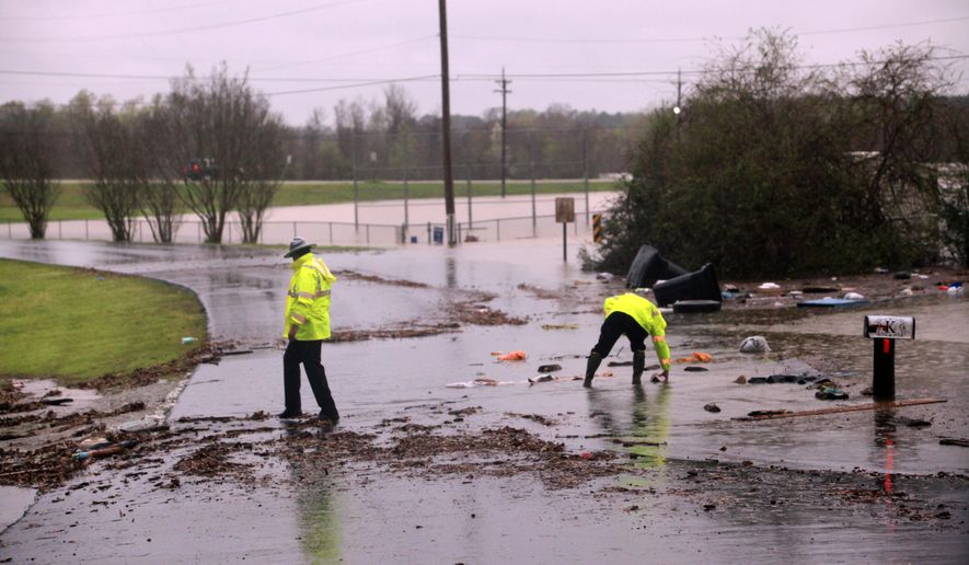 Louisiana State police help clear the road of debris at the entrance in the Tall Timbers subdivision in Haughton, La. Wednesday March 9, 2016. Severe thunderstorms have caused major flooding and closed all schools in the area. Several parishes in northwest Louisiana have declared a state of emergency over widespread flooding, and the National Guard is being sent in to help. (AP Photo/Mike Silva)