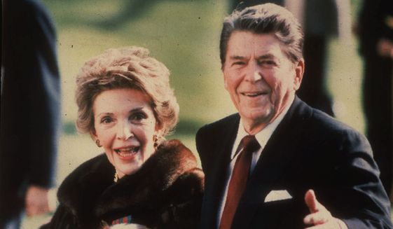 This December 1986 file photo shows first lady Nancy Reagan holding the Reagans&#39; pet Rex, a King Charles spaniel, as she and President Reagan walk on the White House South lawn. The former first lady will be buried beside her &quot;Ronnie&quot; Friday, March 11, 2016, at the library they loved, after being mourned and celebrated by family and hundreds of friends from Hollywood, Washington and beyond in a private service. Mrs. Reagan, who died Sunday at 94, planned the smallest details of her funeral. (AP Photo/Dennis Cook, File)