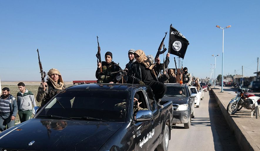 In this this file photo released on May 4, 2015, on a militant website, which has been verified and is consistent with other AP reporting, Islamic State militants pass by a convoy in Tel Abyad, northeast Syria. (Militant website via AP, File)