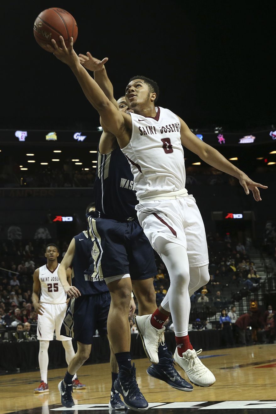 Saint Joseph guard Lamarr Kimble (0) goes to the basket past George Washington forward Kevin Larsen during the first half of an NCAA college basketball game in the Atlantic 10 men's tournament, Friday, March 11, 2016, at New York. (AP Photo/Mary Altaffer)