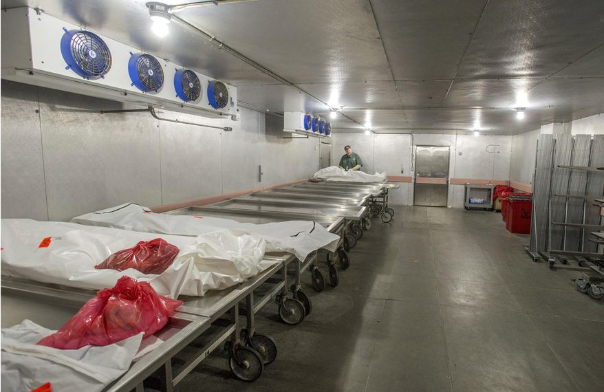 In this March 4, 2016, Jim Eggleston, a death investigator, closes a bagged body in the cooler at the Pierce County Medical Examiner's offices in Tacoma, Washington. (Peter Haley/The News Tribune via AP)
