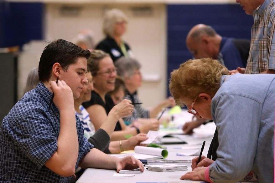 Nathan Bailey, 16, a student election official at the Bernard School voting site, helps Virginia Hammack sign in for voting, Tuesday, March 15, in St. Louis, Mo. Voters in Missouri, as well as Illinois, Florida, Ohio and North Carolina are casting their ballots in primary elections Tuesday. (Cristina M. Fletes/St. Louis Post-Dispatch via AP) ** FILE **