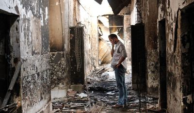 FILE - In this Oct. 16, 2015, file photo, an employee of Doctors Without Borders walks inside the charred remains of the organization&#39;s hospital after it was hit by a U.S. airstrike in Kunduz, Afghanistan. More than a dozen U.S. military personnel have been disciplined but face no criminal charges for mistakes that led to the bombing of a Doctors Without Borders hospital in Afghanistan last year that killed 42 Afghans, U.S. defense officials say. (AP Photo/Najim Rahim, File)
