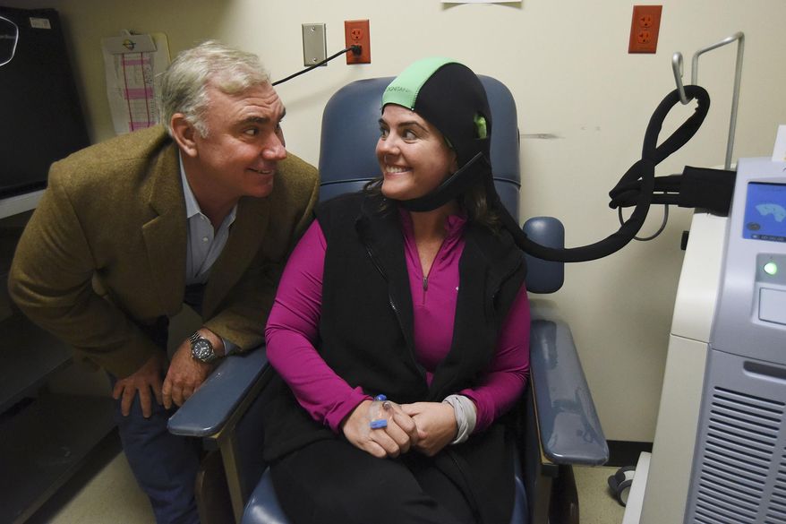 In this Friday, Feb. 26, 2016 photo, Adrianne Frost, who is wearing the Dignicap which will allow her to keep her hair as she undergoes chemotherapy for breast cancer, smiles at her husband, Tom Kelly, at the Cancer Therapy and Research Center in San Antonio, Texas. Frost is the first person in America, other than in clinical trials, to use the device. (Billy Calzada/The San Antonio Express-News via AP) RUMBO DE SAN ANTONIO OUT; NO SALES; MANDATORY CREDIT