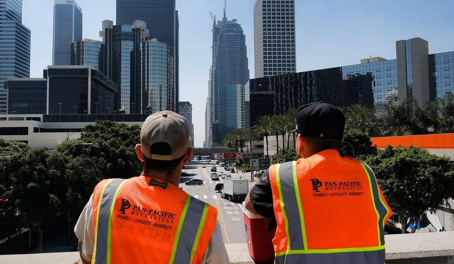 Maintenance workers look down South Figueroa Street toward a skyscraper under construction where a worker fell to his death on Thursday, March 17, 2016. (AP Photo/Richard Vogel)