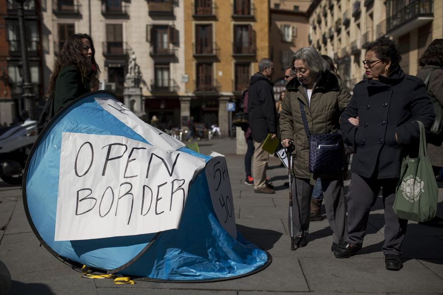 Passers-by look at a tent set up during a symbolic protest against the European Union proposals to deport refugees back to Turkey, in Madrid, Wednesday, March 16, 2016. Leaders of the EU's 28 divided nations plan to reconvene in Brussels this week in hopes of ironing out disagreements on a proposed agreement with Turkey in the migrants crisis. (AP Photo/Francisco Seco)