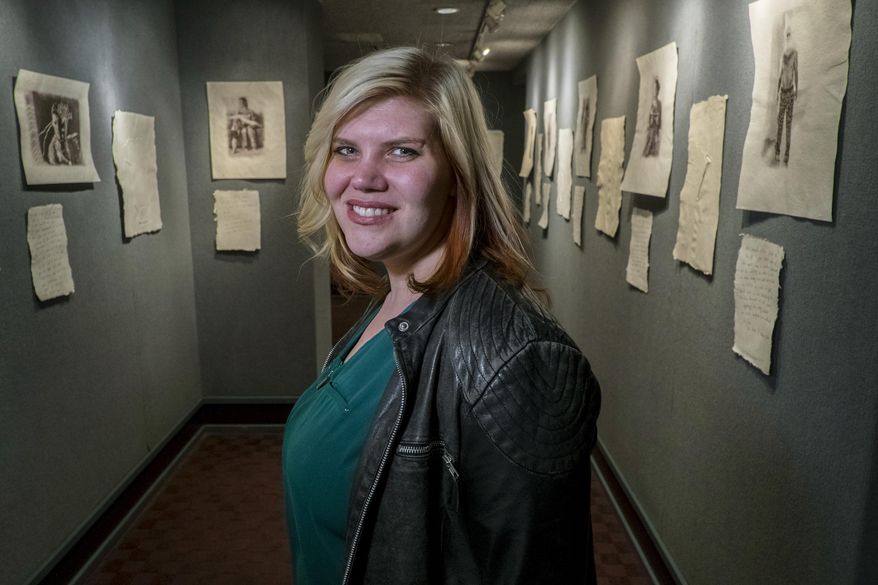 ADVANCE FOR SATURDAY, MARCH 19, 2016- In this Feb. 26, 2016, photo, photographer and artist Trish Brownlee poses with her work at the Cape Fear Regional Theatre in Fayetteville, N.C. Brownlee's art exhibit tells soldiers' stories and aims to bridge the gap between military and civilian worlds. (Raul R. Rubiera /The Fayetteville Observer via AP) MANDATORY CREDIT