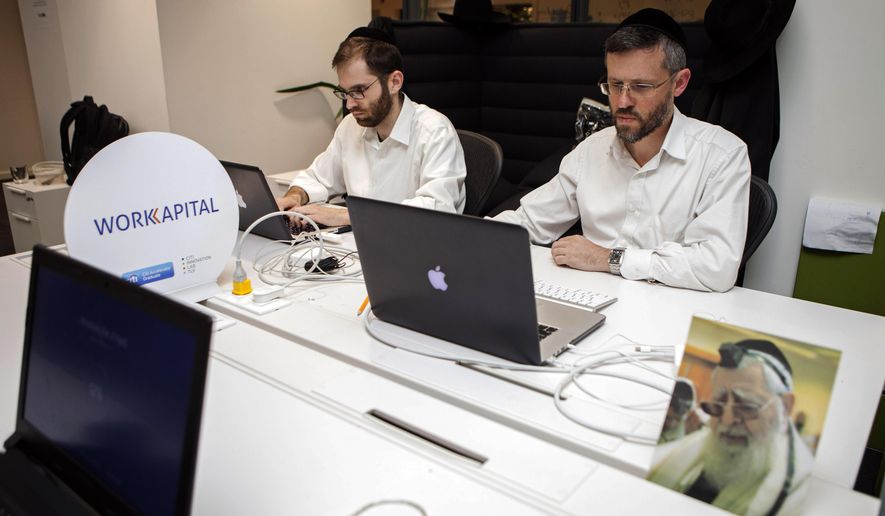 In this photo taken Tuesday, March 15, 2016, ultra-Orthodox Jewish men work at a high tech start-up in an office in Tel Aviv. More and more, young ultra-Orthodox insist they can continue to lead pious lives while also embracing technology, the modern workplace and their fellow Israelis. (AP Photo/Dan Balilty)