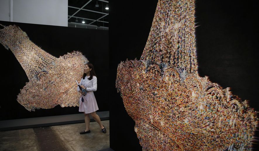 A woman walks past an artwork &amp;quot;Chandeliers for Five Cities&amp;quot; created by South Korean artist Ham Kyungah during the VIP preview of the art fair &amp;quot;Art Basel&amp;quot; in Hong Kong, Tuesday, March 22, 2016. Ham presented &amp;quot;Chandeliers in Five Cities,&amp;quot; the latest in her series of embroidered works crafted with the help of unidentified North Korean workers. Ham settled on chandeliers as a reference to political power after she noticed one in a picture of world leaders meeting to divide the Korean Peninsula into north and south at the end of World War II. (AP Photo/Kin Cheung)