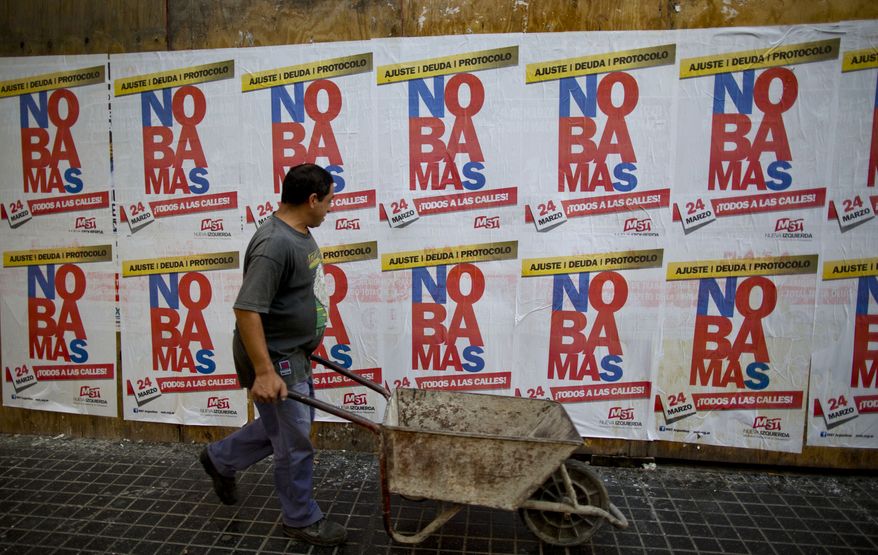 A man passes in front of banners reading in Spanish "No more" in protest against the visit of United States President Barack Obama in Buenos Aires, Argentina, Wednesday, March 23, 2016. Obama is on a two-day visit to Argentina and will meet Wednesday with Argentine President Mauricio Macri. (AP Photo/Ivan Fernandez)
