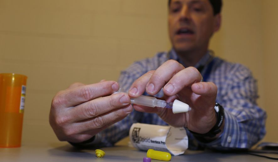 In this Tuesday, March 1, 2016, photograph, Dr. Josh Blum demonstrates how to administer a dose of naloxone while conferring with the inmate at the Denver County Jail in downtown Denver. Jails and correction agencies across the country such as Denver are teaching soon-to-be-released inmates how to use the heroin overdose antidote called naloxone, either to save others and sometimes themselves. (AP Photo/David Zalubowski) ** FILE **