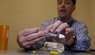 In this Tuesday, March 1, 2016, photograph, Dr. Josh Blum demonstrates how to administer a dose of naloxone while conferring with the inmate at the Denver County Jail in downtown Denver. Jails and correction agencies across the country such as Denver are teaching soon-to-be-released inmates how to use the heroin overdose antidote called naloxone, either to save others and sometimes themselves. (AP Photo/David Zalubowski) ** FILE **