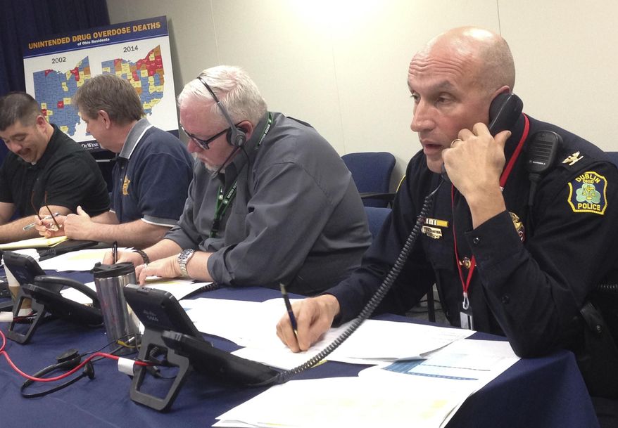 Dublin Police Chief Heinz von Eckartsberg, right, calls a law enforcement agency in Ohio to talk about the availability of the drug-overdose antidote naloxone, as fellow phone bank participants work nearby at the state attorney genera's office on Thursday, March 24, in Columbus, Ohio. Staff from the Ohio attorney general's office joined those from several agencies to host a phone bank aimed at informing local entities about how to get naloxone. (AP Photo/Ann Sanner)