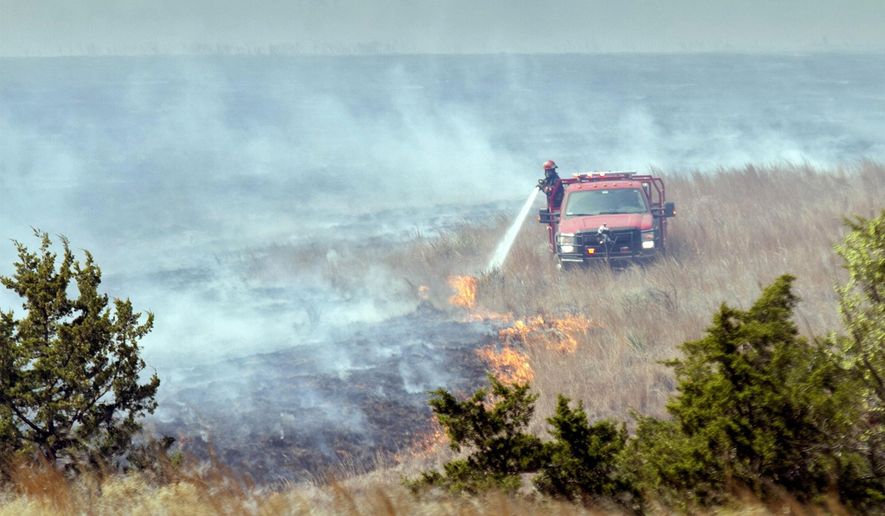 A firefighter crew douses a line of grass fire about 15 miles southwest of Medicine Lodge, Kansas Thursday, March 24, 2016. More than 200 firefighters are battling an active fire line stretching 30 to 40 miles long in Barber County on Thursday. (Mike Hutmacher/The Wichita Eagle via AP) LOCAL TELEVISION OUT; MAGS OUT; LOCAL RADIO OUT; LOCAL INTERNET OUT; MANDATORY CREDIT