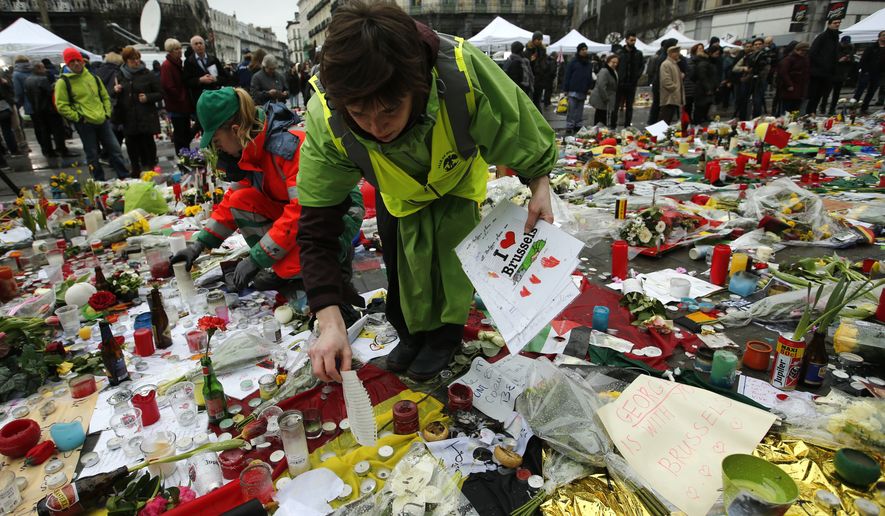Workers from the City of Brussels collect some of the tributes to preserve them at one of the memorial sites, after the recent attacks in the capital at the Place de la Bourse in Brussels, Friday, March, 25, 2016. (AP Photo/Alastair Grant)