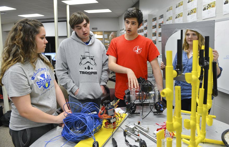 ADVANCE FOR THE WEEKEND OF MARCH 26-27 AND THEREAFTER - In a Tuesday, March 15, 2016 photo, with the help of a mock course, Lost Rockets team members, from left, Kaitlyn Abernathy, Blake Bennett, Tristan Jay and Lauren Simpson show how their underwater robot will have to operate during the competition, at the Limestone Career Technical Center in Athens, Ala. After 20 years of competing in land-based robotics competitions, students at the Limestone Career Technical Center are taking their skills beneath the waves. For the first time, the school will compete in an underwater robotics competition to take place next month at the Dauphin Island Sea Lab. (Jeronimo Nisa/The Decatur Daily via AP) MANDATORY CREDIT