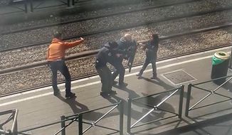 In this image taken from video filmed through a window, showing armed police as they coax a young girl away from a suspect who is laying on the ground at a tram stop in Brussels, Belgium, Friday March 25, 2016.   During an interview with The Associated Press on Sunday March 27, 2016, eyewitness Gracia Meta, describes how the unidentified young girl stood up and walked to the police and is then led away from the scene. (UGC via AP)