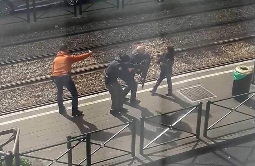 In this image taken from video filmed through a window, showing armed police as they coax a young girl away from a suspect who is laying on the ground at a tram stop in Brussels, Belgium, Friday March 25, 2016.   During an interview with The Associated Press on Sunday March 27, 2016, eyewitness Gracia Meta, describes how the unidentified young girl stood up and walked to the police and is then led away from the scene. (UGC via AP)