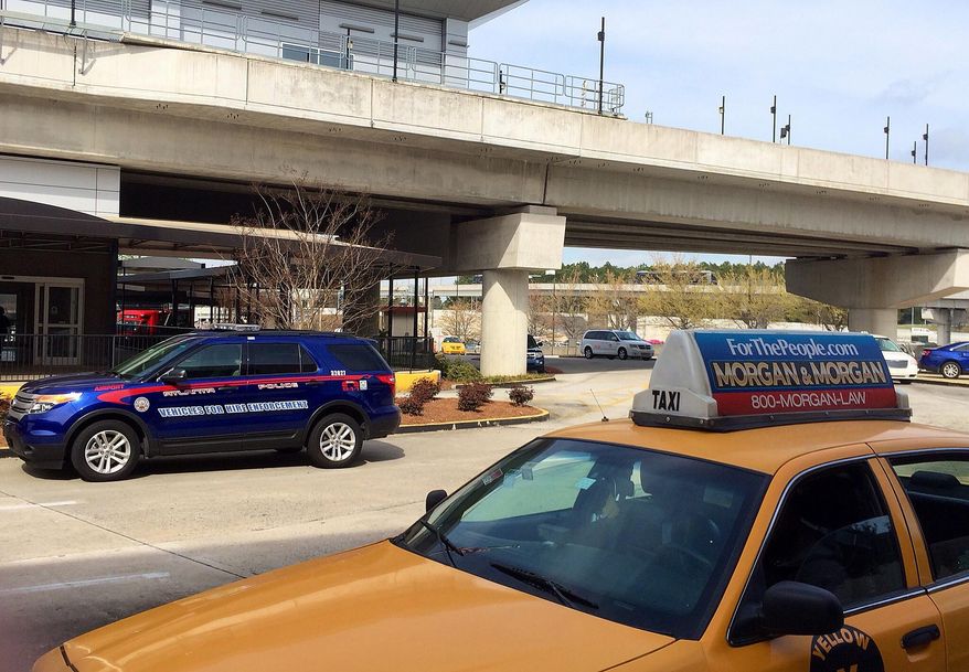 In this March 25, 2016 photo, an Atlanta Police Rides-For-Hire Enforcement vehicle sits amid taxi cabs outside the departures area of the domestic terminal at Hartsfield-Jackson Atlanta International Airport. A battle over background checks for Uber drivers at the world's busiest airport comes as cities like Los Angeles and Austin, Texas, consider more thorough screenings to prevent criminals from getting behind the wheel. Uber has objected to the use of fingerprints to check criminal records of its drivers, saying its own record checks are sufficient. (AP Photo/Jeff Martin)
