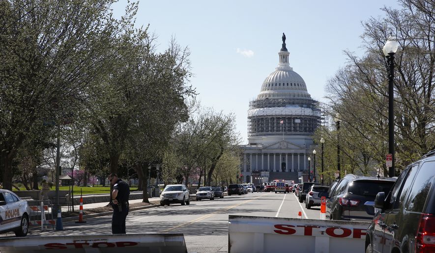 An officer stands guard on a street leading to Capitol Hill in Washington that is closed, Monday, March 28, 2018, after reports of gunfire at the Capitol Visitor Center complex. (AP Photo/Alex Brandon)