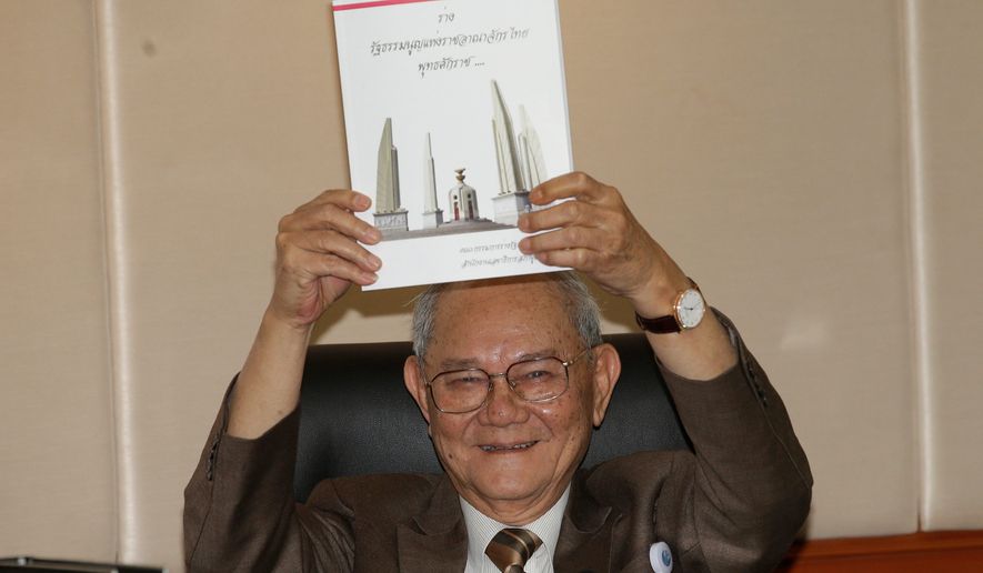 Chairman of the Constitution Drafting Commission Meechai Ruchupan holds the draft of new constitution during a press conference at the Parliament in Bangkok, Thailand, Tuesday. The junta chief said it will permit about 50 million eligible voters to vote on its constitution in a referendum on Aug. 7 (Associated Press)