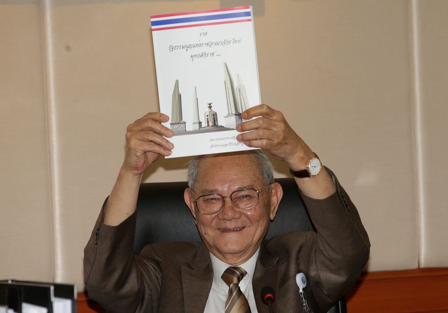 Chairman of the Constitution Drafting Commission Meechai Ruchupan holds the draft of new constitution during a press conference at the Parliament in Bangkok, Thailand, Tuesday. The junta chief said it will permit about 50 million eligible voters to vote on its constitution in a referendum on Aug. 7 (Associated Press)