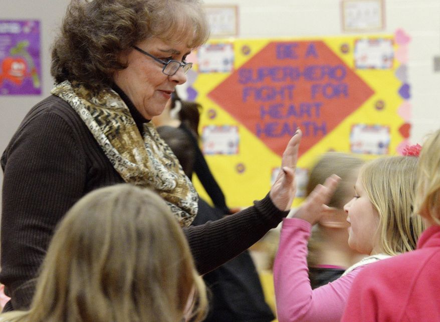 In this March 2, 2016 photo, Rosemary Martin, a long-time physical education teacher at Heyworth Elementary School in Heyworth, Ill., high-fives second-grader Kamryn Whitwood in the school gym during a P.E. class. Martin has a long-standing practice of integrating heart health lessons into P.E. class. She has decorated the gym walls with posters promoting heart health. (Steve Smedley/The Pantagraph via AP) MANDATORY CREDIT