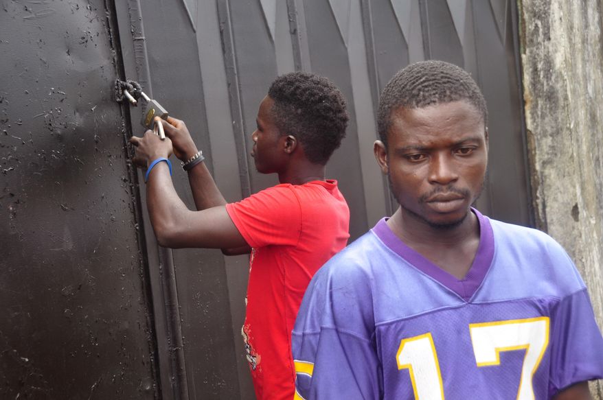 In this photo taken Saturday, March 26, 2015, community chairman Albert Reeves, foreground, at the crematorium were he used to work in Boys Town on the outskirts of Monrovia, Liberia. As Liberia marks the second anniversary Wednesday of its first confirmed Ebola cases, many neighbors say they want to see the crematorium torn down so they can try to forget that terrible time. (AP Photo/ Abbas Dulleh)