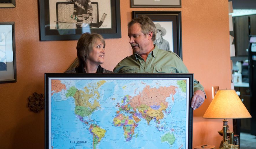 ADVANCE FOR WEEKEND EDITIONS, APRIL 2-3 - In this photo taken, Feb. 16, 2016, Marsha and Clay Neubert, of Powell, Wyo, pose with a world map with pins that identify all the countries where Clay Neubert’s artwork is on display. Neubert has created Pepsi artwork since 1987. From Iran to Ireland, Australia to Algeria, China to the Czech Republic, Neubert’s artwork is featured in Pepsi businesses around the world. (Carla Wensky/The Powell Tribune via AP) MANDATORY CREDIT