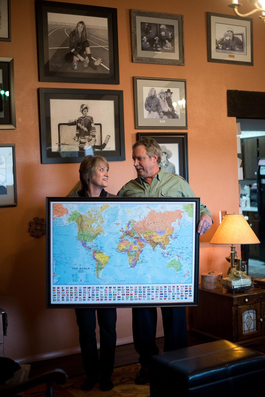 ADVANCE FOR WEEKEND EDITIONS, APRIL 2-3 - In this photo taken, Feb. 16, 2016, Marsha and Clay Neubert, of Powell, Wyo, pose with a world map with pins that identify all the countries where Clay Neubert’s artwork is on display. Neubert has created Pepsi artwork since 1987. From Iran to Ireland, Australia to Algeria, China to the Czech Republic, Neubert’s artwork is featured in Pepsi businesses around the world. (Carla Wensky/The Powell Tribune via AP) MANDATORY CREDIT