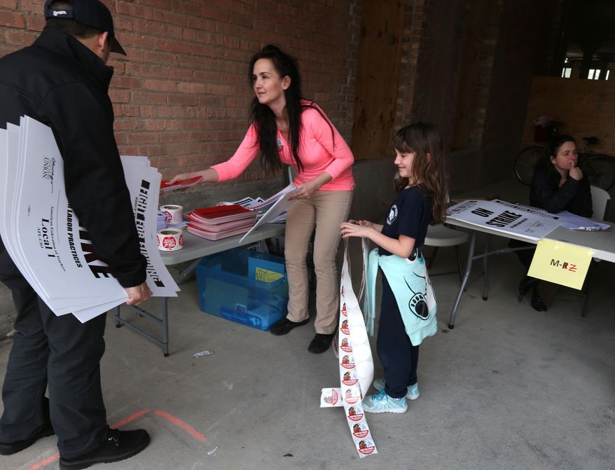 In this Wednesday, March 30, 2016 photo, seventh-grade teacher Katherine Gallingly, of Portage Park Elementary School, center, and her daughter, Caitlin, 7, assist with signs at the Chicago Teachers Union headquarters in Chicago and in preparation for Friday's one-day teachers strike. The teachers union and other community groups and unions are calling for more state funding for schools and social services. (Phil Velasquez /Chicago Tribune via AP))