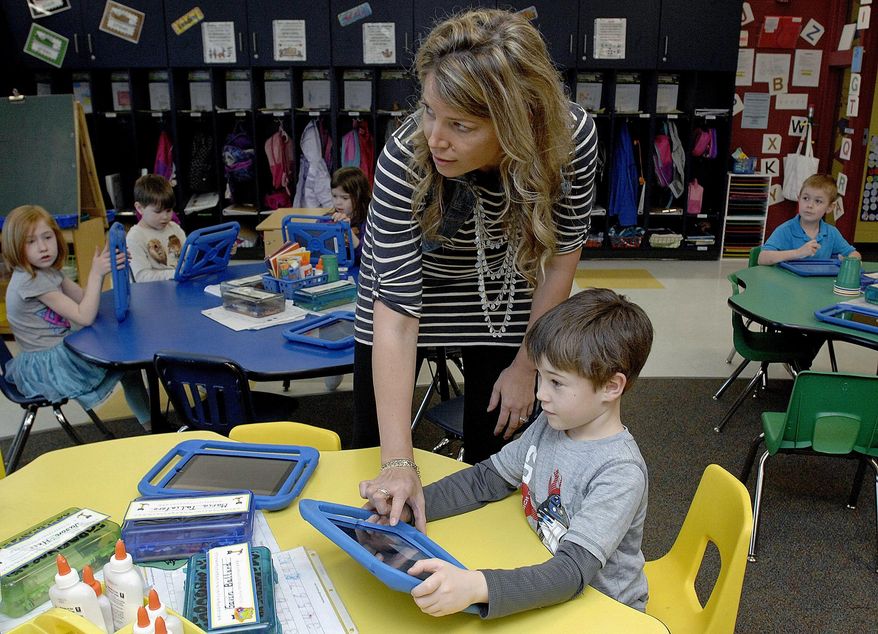 ADVANCE FOR USE SATURDAY, APRIL 2 AND THEREAFTER - In this March 13, 2016 photo, Olympia North Elementary School kindergarten teacher Laura Baner puts Gavin Ballard's work on the video board from his work on the iPad during class in rural Stanford, Ill. (Lori Ann Cook-Neisler/The Pantagraph via AP) MANDATORY CREDIT