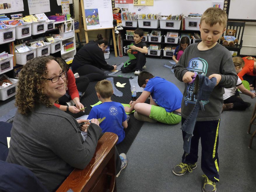 In this March 10, 2016 photo, Shelly Echternkamp, left, joins son Aiden, 7, and other students and family members in cutting patterns for denim shoes at Ellington School in Quincy, Ill. Ellington classes are partnering with Sole Hope, a North Carolina-based organization that puts closed-toe shoes on African children. Making the shoe pieces is part of a yearlong service learning project designed to broaden the horizons and leadership skills of Ellington students. (Steve Bohnstedt/The Quincy Herald-Whig via AP) MANDATORY CREDIT
