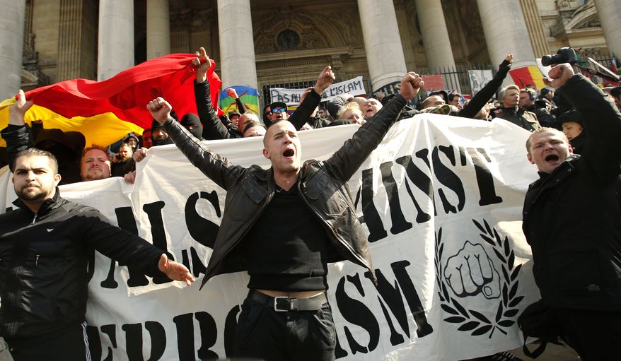 FILE - In this Sunday, March, 27, 2016 file photo, right-wing demonstrators chant slogans next to one of the memorials to the victims of the recent Brussels attacks, at the Place de la Bourse in Brussels. As extreme-right groups threaten to take Molenbeek neighborhood by storm Saturday, April 2, community leaders fear its predominantly Muslim young people will fight back. “They don’t trust the police and they aren’t going to take it,” said Fouad Ben Abdelkader, a teacher in the neighborhood. On Thursday he joined a meeting of a couple dozen community leaders and mentors to neighborhood youths who feel adrift in mainstream Belgian society. The group of community organizers was looking for ways to head off an escalation of violence in the largely Muslim neighborhood, hoping to avoid a situation like occurred last Sunday when hundreds of black-clad hooligans shouting Nazi slogans disrupted a memorial at Brussels’ Bourse square for the 32 victims of the March 22 attacks on the airport and subway system. (AP Photo/Alastair Grant, file)