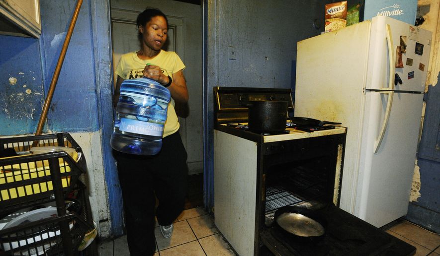 Renea Robinson talks about the problems she is having, carrying in containers of water for cooking, due to not having running water in the kitchen on March 24, 2016 in Detroit. Detroit last year shut off water service to 23,300 homes while leaving the taps running at thousands of businesses that owe millions of dollars, according to the Detroit News review of documents published Friday, April 1. Robinson, a single mother of four young children who works two jobs, has lived without water for six months after the house she rented for seven years went into foreclosure because the landlord didn't pay taxes or the $5,000 water bill. (Daniel Mears/Detroit News via AP) DETROIT FREE PRESS OUT; HUFFINGTON POST OUT; MANDATORY CREDIT MBO (REV-SHARE)