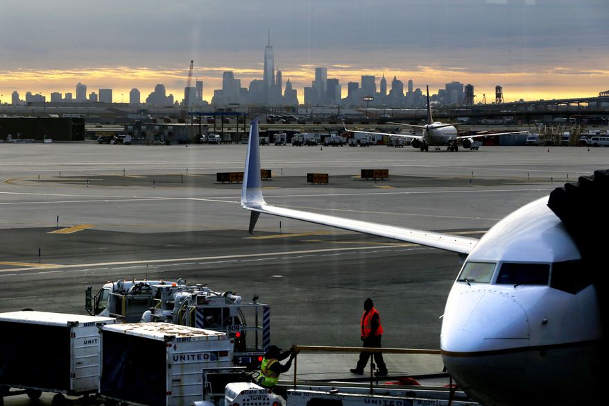 FILE - In a May 1, 2015 file photo, a United Airlines employee walks near a jet parked at Terminal C of Newark Liberty International Airport as the sun rises behind the New York City skyline, in Newark, N.J. The Federal Aviation Administration announced Friday, April 1, 2016, that it is easing limits on the number of hourly flights at Newark Liberty International Airport, and the airport’s operator said that should lead to greater competition and lower fares.(AP Photo/Julio Cortez, File)