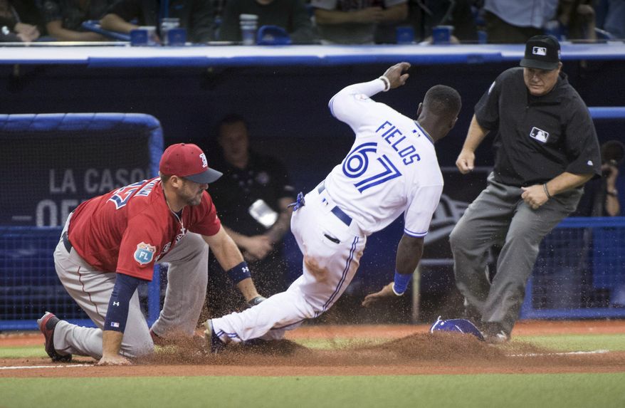 Toronto Blue Jays' Roemon Fields is tagged out while trying to steal third by Boston Red Sox third baseman Travis Shaw as umpire Toby Basner watches during the ninth inning of an exhibition baseball game Friday, April 1, 2016, in Montreal. (Paul Chiasson/The Canadian Press via AP)