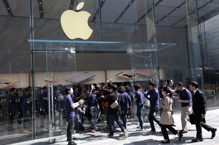 FILE - In this Thursday, March 31, 2016, file photo, Apple employees cheer at the door as they escort first customers in line for the release and sale start of the new Apple iPhone SE at an Apple shop in Tokyo. The revelation that the FBI was able to break into a secured iPhone without Apple’s help won’t take a bite out of Apple’s brand reputation, but consumers will be looking for security improvements soon. (AP Photo/Eugene Hoshiko, File)