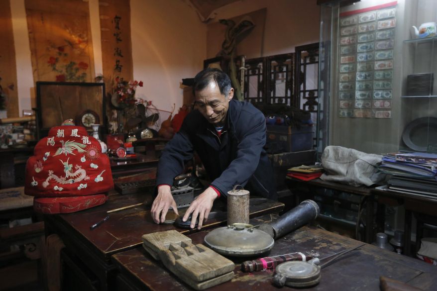 In this Tuesday, March 22, 2016 photo, Wang Jinming shows his household items and street objects dating from 1900s to the 1970s which he collected at his private museum in Beijing. Wang’s Beijing Old Items Exhibition in the heart of old Beijing is one of dozens of private museums that dot the capital’s backstreets and its suburbs. Their collections feature the grand and mundane - from items salvaged from the garbage to a limousine in which Mao Zedong once rode. (AP Photo/Andy Wong)